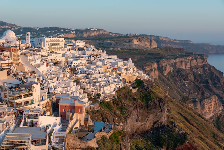 Aerial view of Santorini's stunning clifftop architecture at sunset.