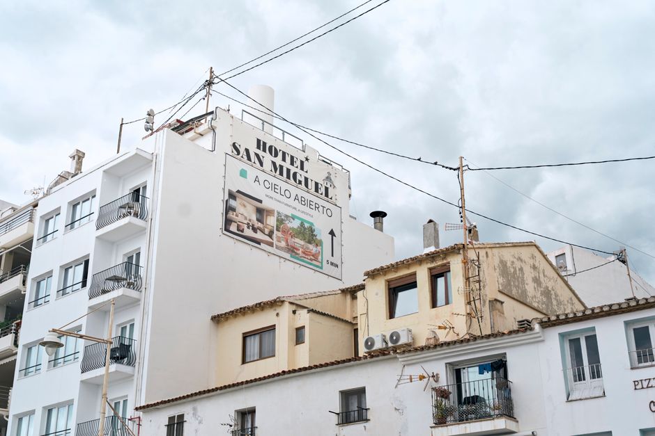 City buildings with a Hotel San Miguel sign, overcast sky background.