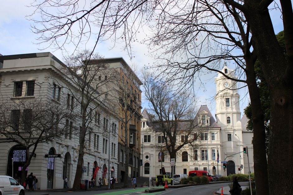 A classic city street with historic buildings and bare winter trees on a bright day.