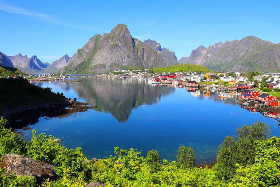 Scenic landscape of Lofoten Islands with clear blue skies and reflections on the water.