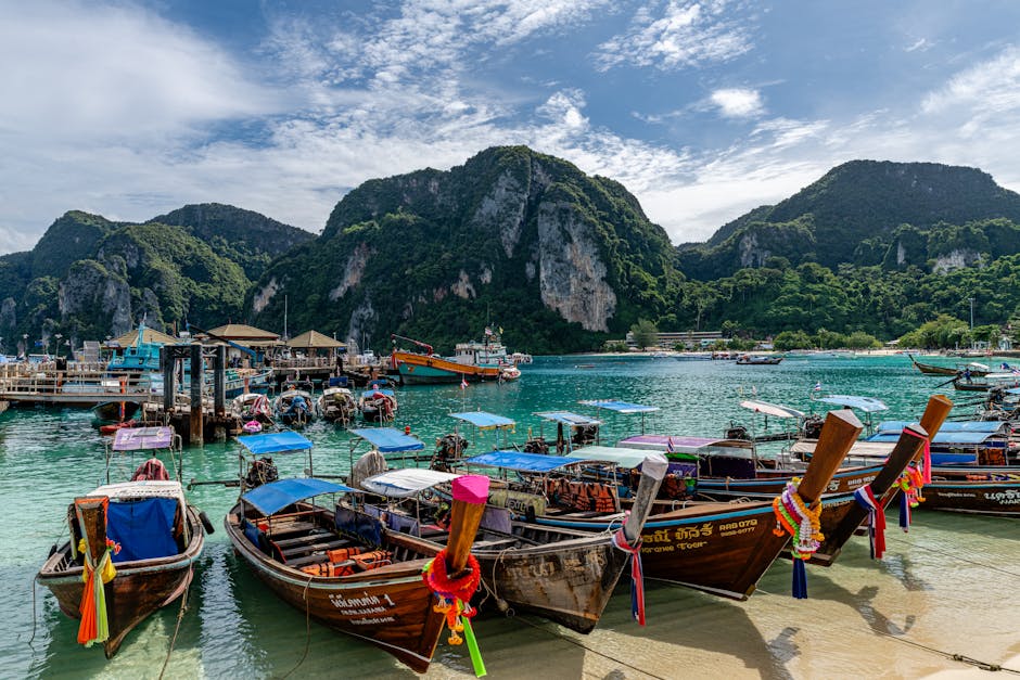 Colorful wooden boats anchored in a picturesque bay with lush hills in Phuket, Thailand.