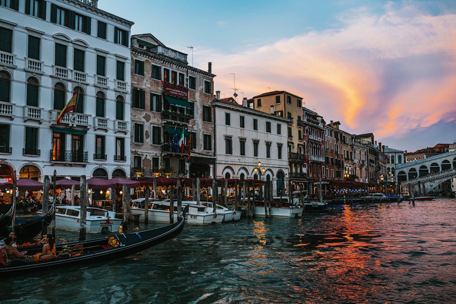 Capture of Venice's Grand Canal at sunset with gondolas and iconic Rialto Bridge.