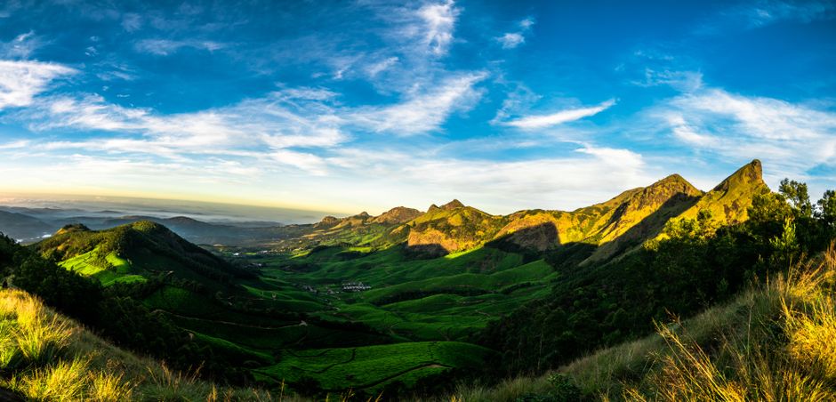 Vibrant landscape of a green valley and majestic mountains under a bright blue sky.
