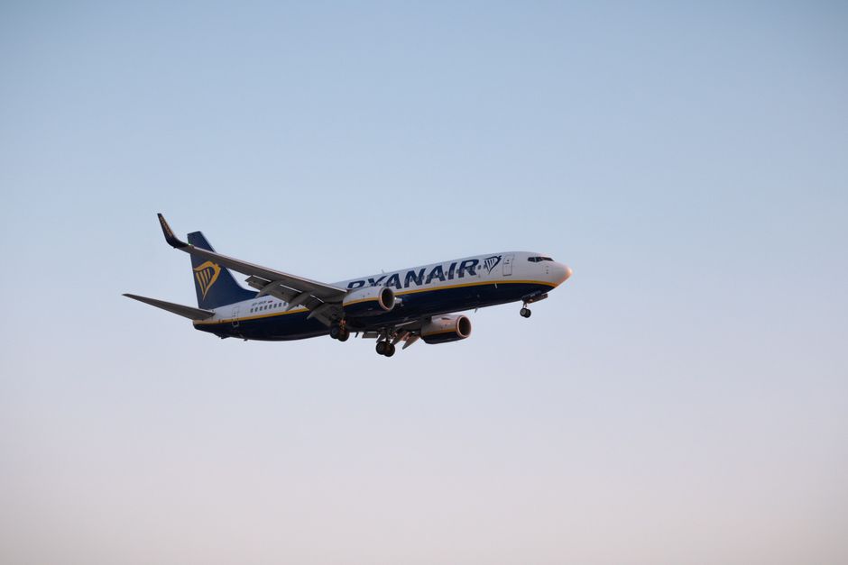 A Ryanair Boeing airplane flying during daytime with a clear blue sky backdrop.