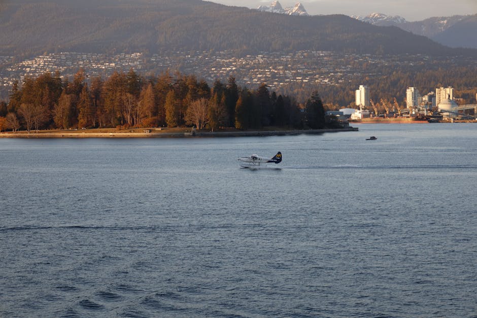 A scenic view of a seaplane in Vancouver harbor with mountains and cityscape in the background.