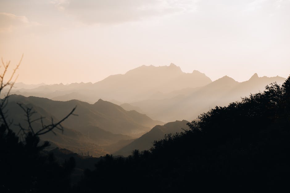 Beautiful view of misty mountains at sunrise in China, with layered silhouettes and gentle fog.
