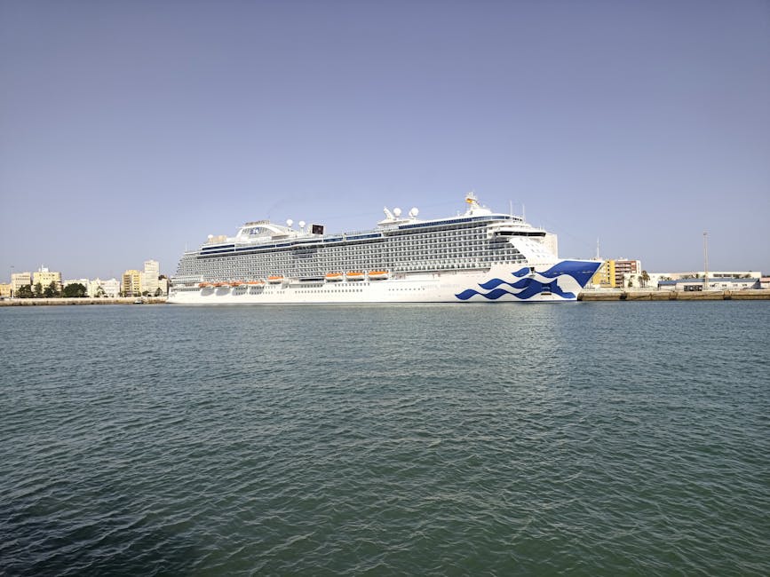 Large cruise ship docked in the scenic harbor of Cádiz, Spain under a clear blue sky.