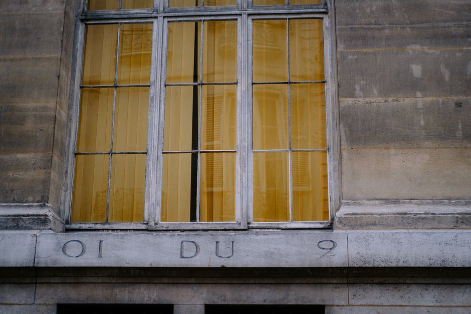 A large window with yellow-tinted glass on a historic stone building, showcasing classic architectural design.