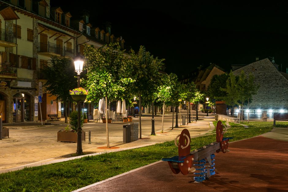 Beautiful night view of a Benasque street with glowing streetlights and lush greenery.