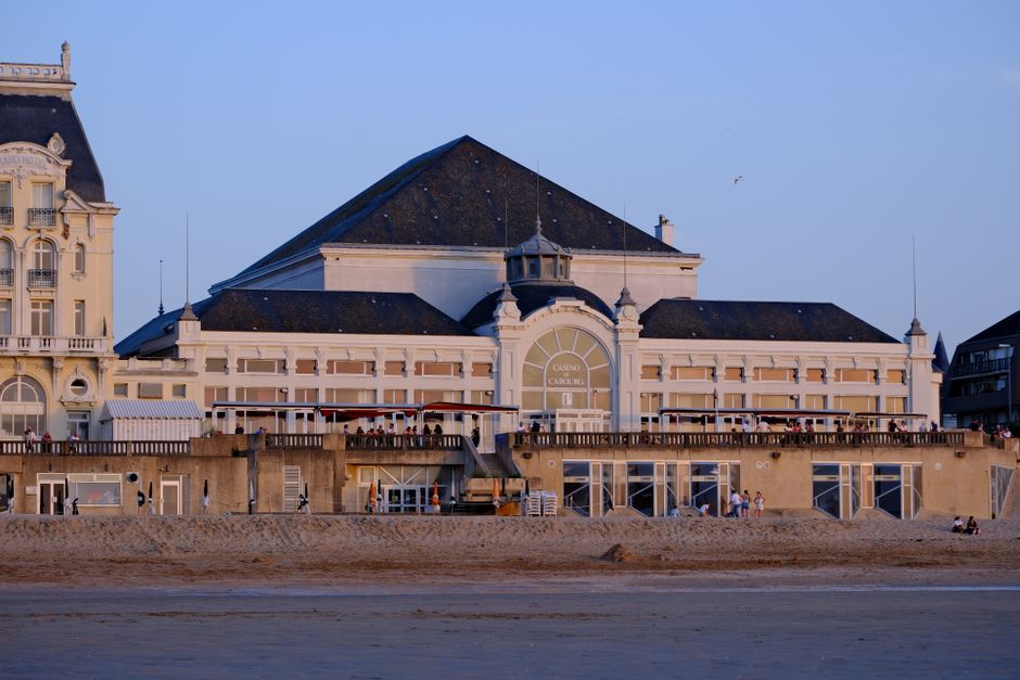Stunning view of Casino de Cabourg's architectural beauty at sunset with golden sand in front.