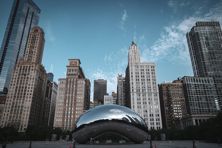 Chicago skyline with Cloud Gate reflecting buildings under a clear sky.