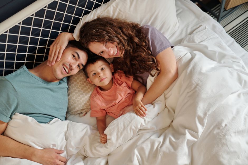 A joyful family of three relaxing together in bed, expressing love and togetherness.