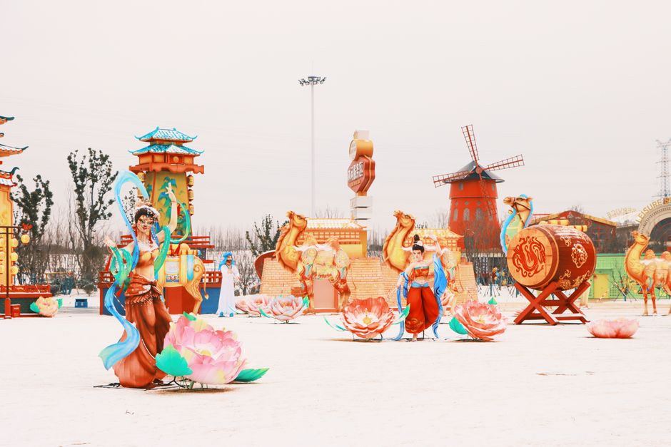 Colorful statues and decorations create an enchanting winter festival scene, featuring cultural motifs and vibrant colors.