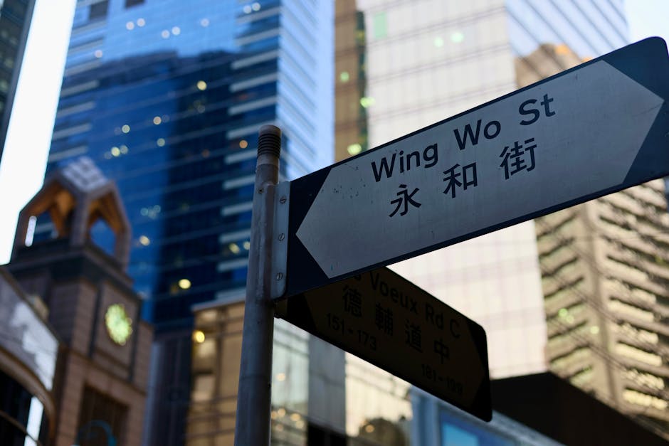 Street sign of Wing Wo Street amidst towering skyscrapers in an urban city setting.