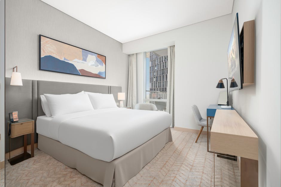 Spacious and elegant modern hotel room featuring a king size bed, contemporary artwork, and a city view.