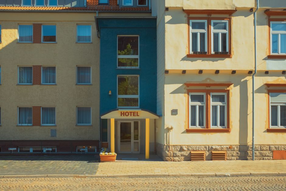 Picturesque facade of a city hotel with warm sunlight and vibrant colors, showing architectural details.
