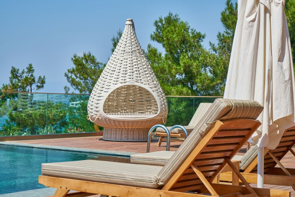 Elegant poolside setting featuring modern loungers and a unique woven chair in a tropical resort.