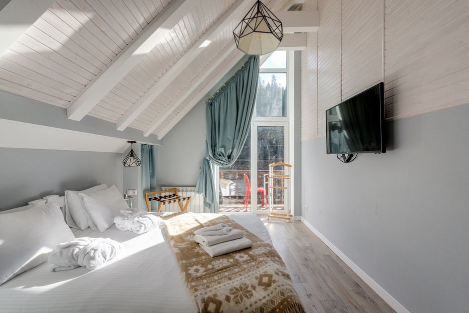 Stylish loft bedroom featuring a cozy bed, large window, and wall-mounted TV.