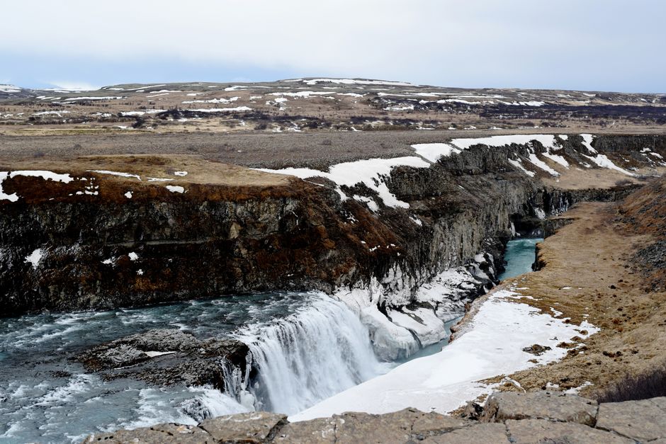 Majestic view of Gullfoss waterfall in Iceland, surrounded by snowy landscape, winter season.