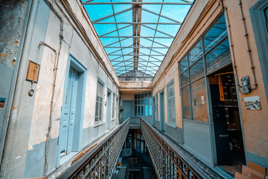 Vintage interior corridor with a glass ceiling showcasing urban decay.