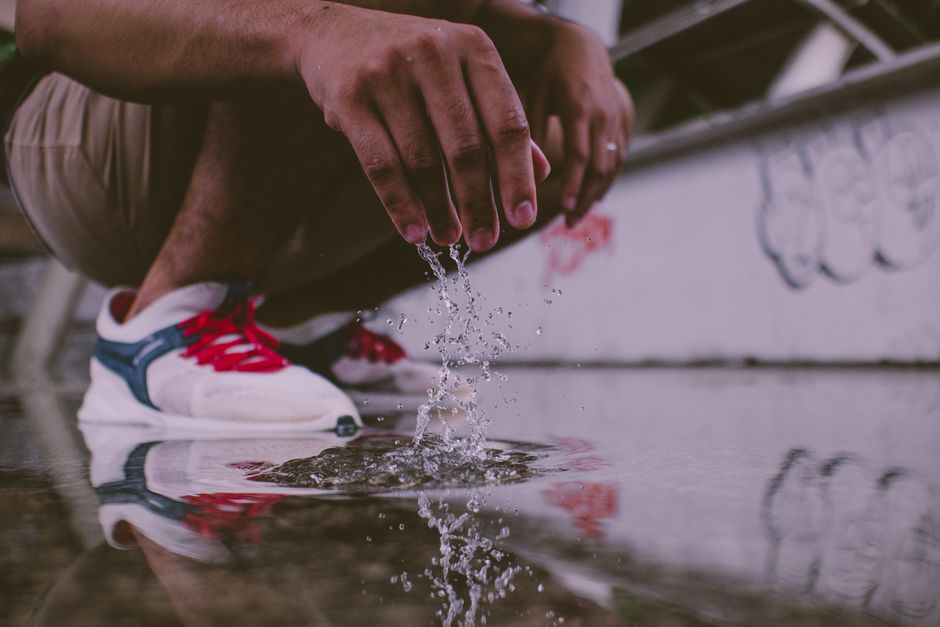 Close-up of a man's hands splashing water on the ground in an urban environment.