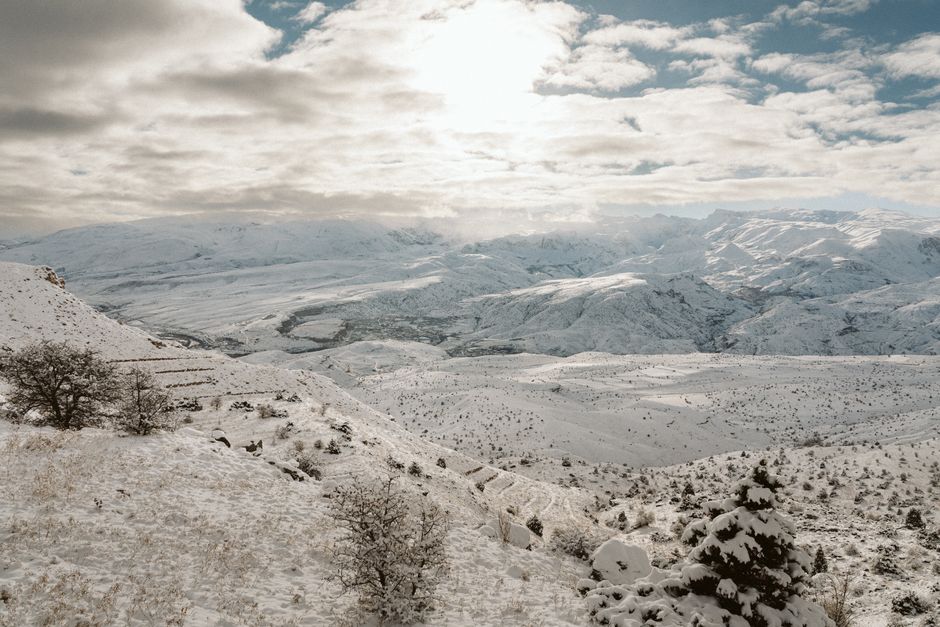 Breathtaking view of snow-covered mountains and valleys under bright winter sky.