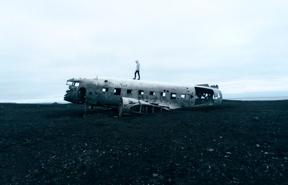 Eerie scene of an abandoned plane wreck on Icelandic beach with a person standing on top.