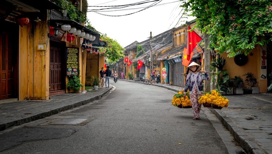 A vibrant street scene in Vietnam featuring a woman carrying flowers in Ho Chi Minh City.
