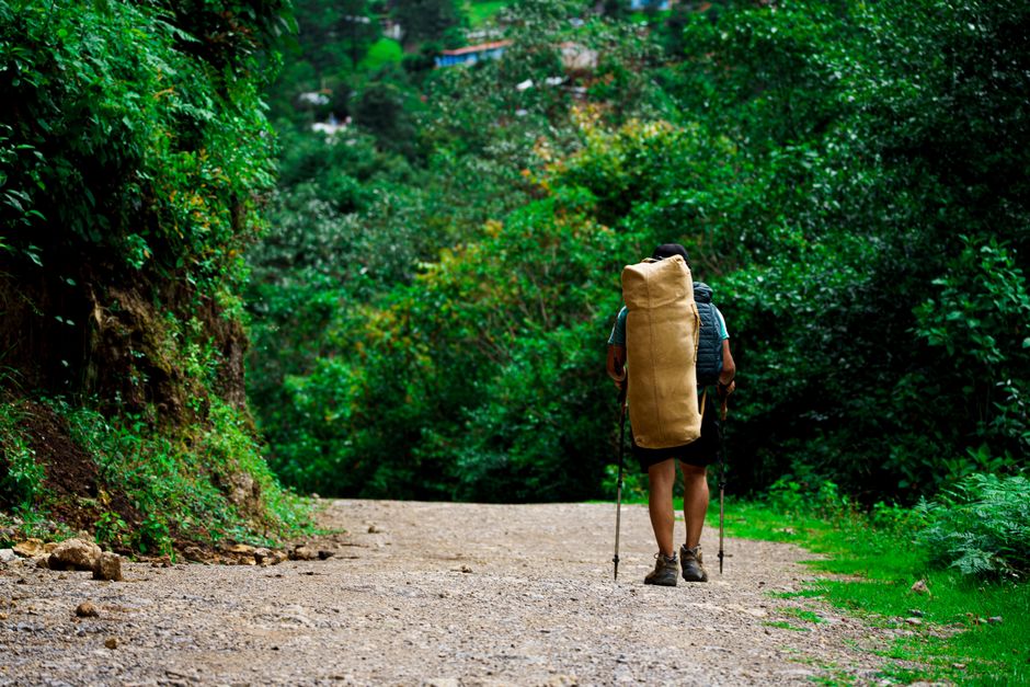 Traveler with backpack hiking on lush green trail in Nebaj, Guatemala.