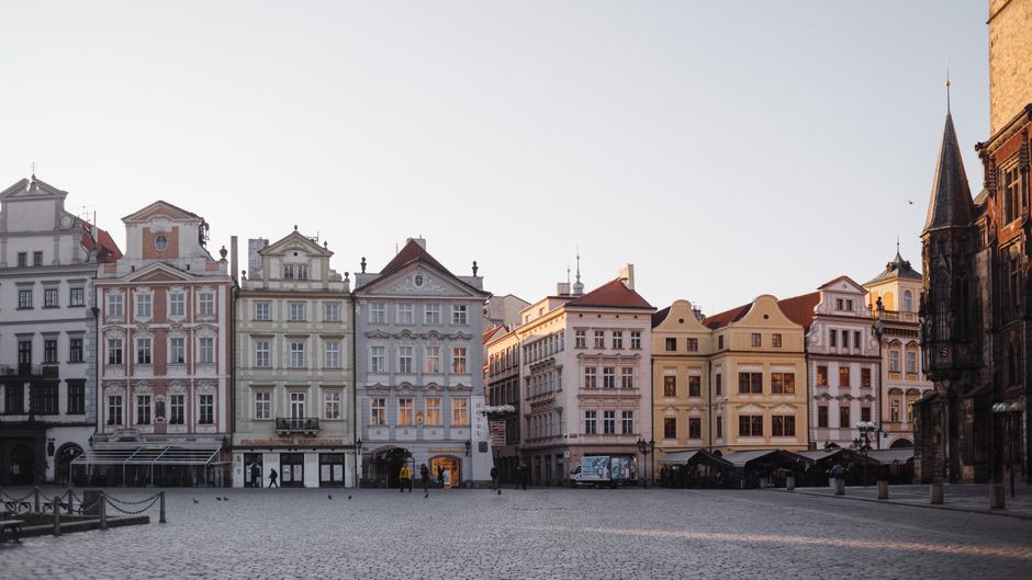 Old fashioned historic bright residential houses lined up next to each other on paved spacious street in city against cloudless sky
