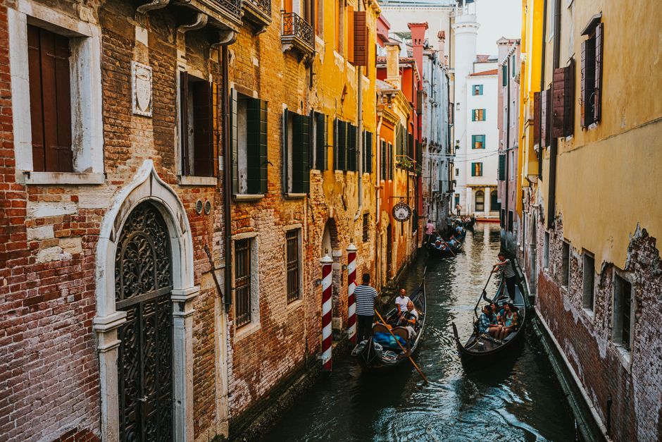 Gondolas navigating a picturesque canal in Venice with vibrant historic buildings.