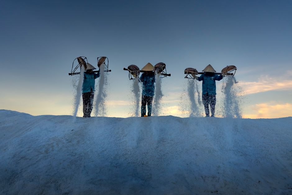 Farm workers harvesting salt at sunrise, showcasing traditional techniques and cultural heritage.