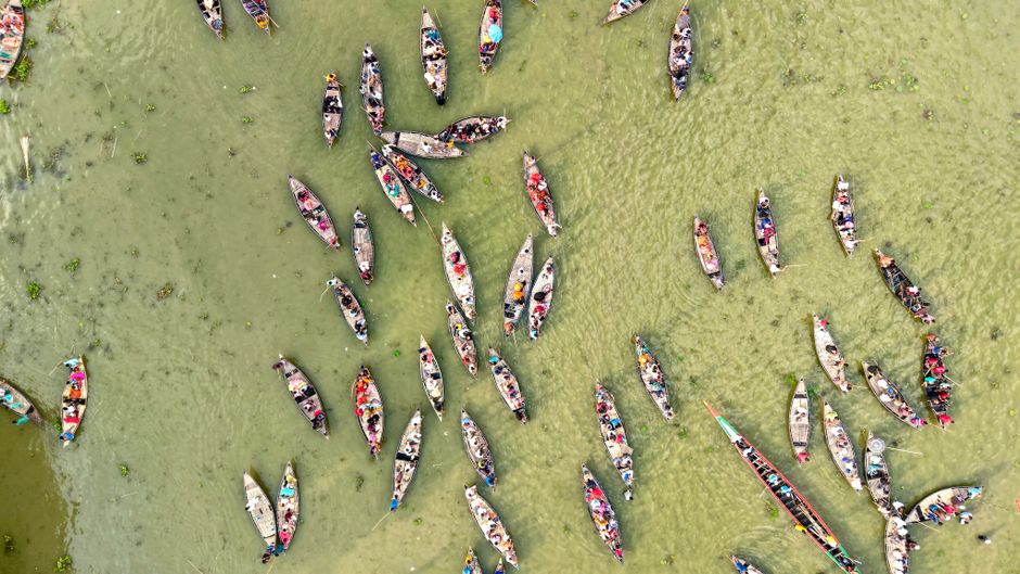 A breathtaking aerial view of colorful wooden boats gathered on a river, bustling with activity and life.