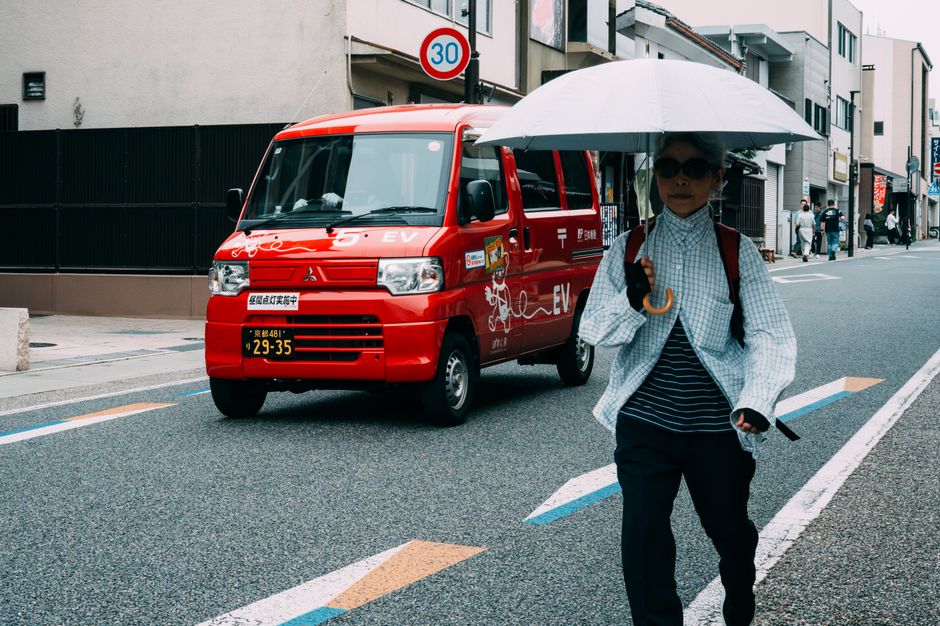 City street view with pedestrian and red postal van captured in daylight.