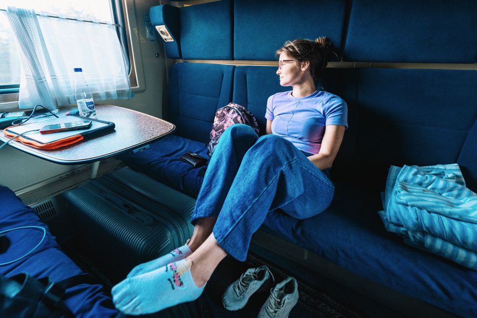 Woman in casual attire enjoying a peaceful train ride, looking thoughtfully out the window.