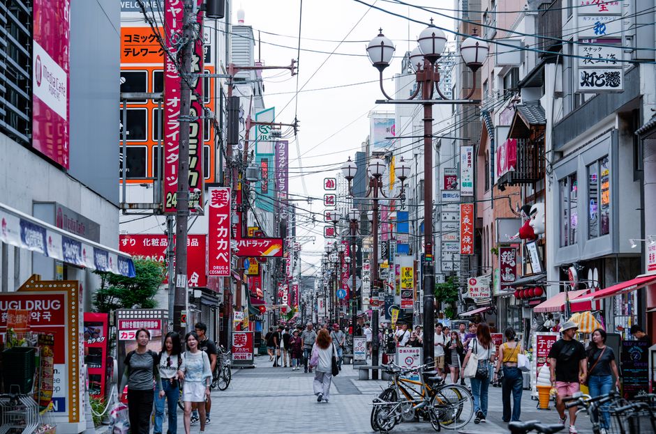 Busy pedestrian street in Osaka with vibrant signs and bustling activity.