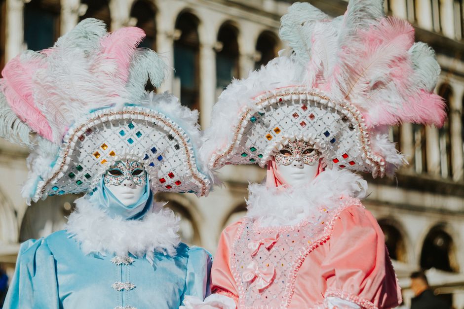 Exquisite Venetian costumes with vibrant feathered hats and intricate masks.