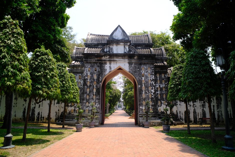 Explore the scenic beauty of a historic archway flanked by lush greenery under a bright day.